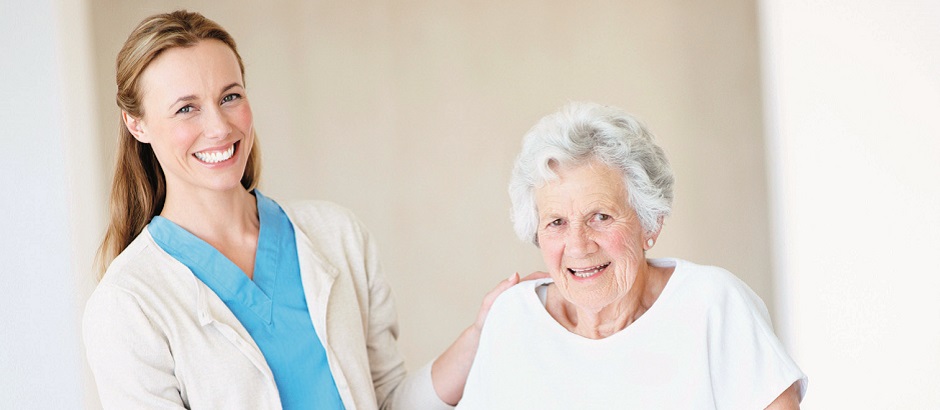 Eine Pflegekraft hilft einer älteren Patientin beim Gehen mit ihrer Gehhilfe