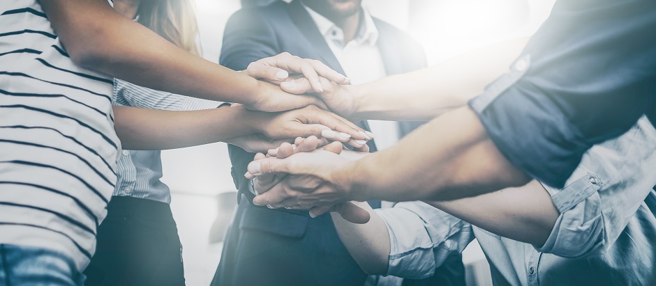 Fünf Personen bilden einen Turm aus Händen, um den Teamgeist zu signalisieren