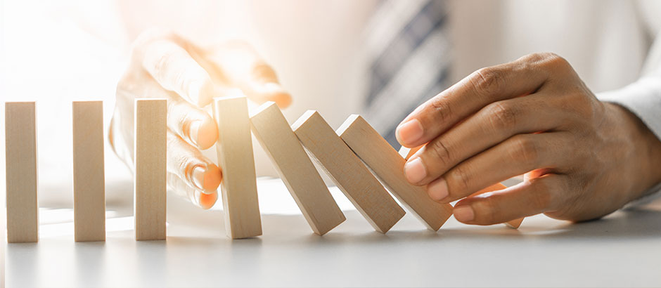 Hand stoppt Dominosteine – symbolisch für Interim Management