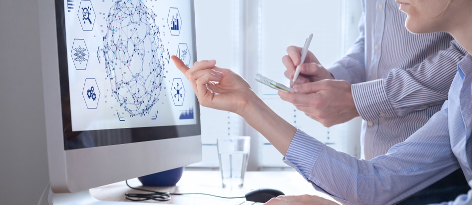 Zwei Personen führen Daten-Analysen auf einem Computer durch